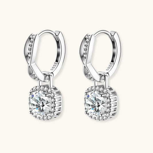 Sterling silver twisted hoop earrings with round moissanite stones in halo settings against neutral background.