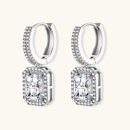 Sterling silver huggie hoops with emerald-cut moissanite drops featuring pavé-set crystals on white background.