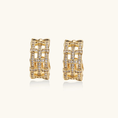 Gold-plated geometric hoop earrings with basket-weave lattice design and pavé crystal accents on cream background