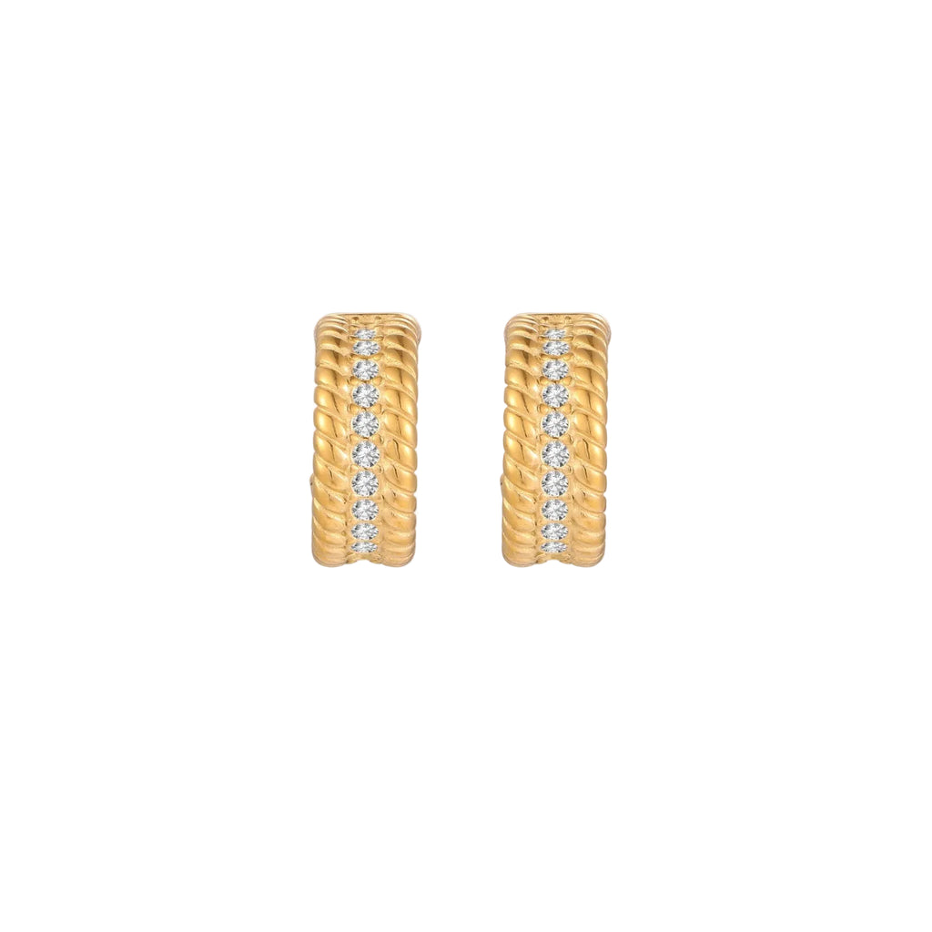 Textured gold huggie hoop earrings with raised ribbed rows creating dimensional sculptural design on cream background